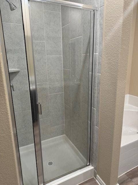 Glass-enclosed shower with gray tiled walls, an integrated shower niche, and a white shower pan
