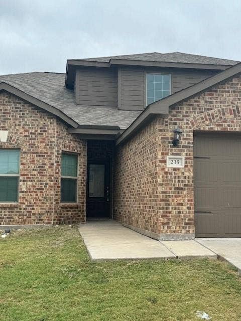 Brick facade with coordinating siding accents, an attached garage, and a covered entry