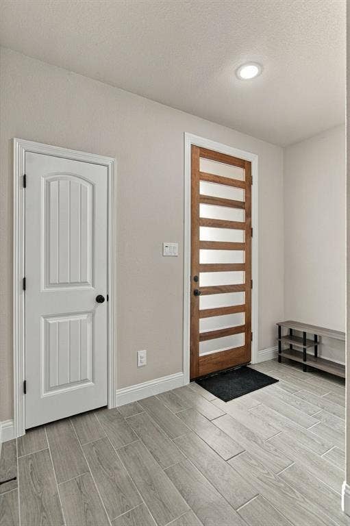4822 Wichita Street, Granbury, TX 76048 Entryway featuring wood-finish tile flooring, recessed ceiling lighting, and a modern wooden entry door with frosted glass panels