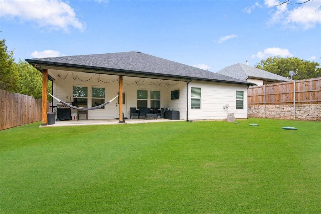 4822 Wichita Street, Granbury, TX 76048 Expansive backyard with a covered patio, wood posts, and a white siding exterior