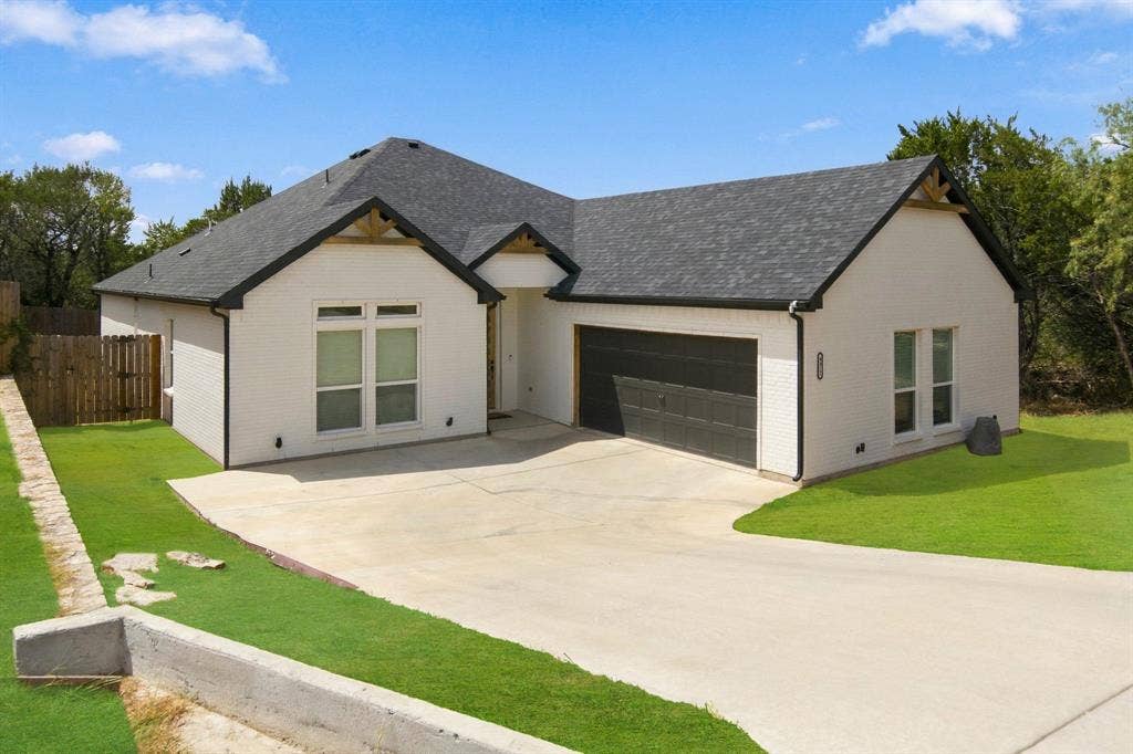 4822 Wichita Street, Granbury, TX 76048 Modern exterior with white brick, dark trim, a two-car garage, and a concrete driveway