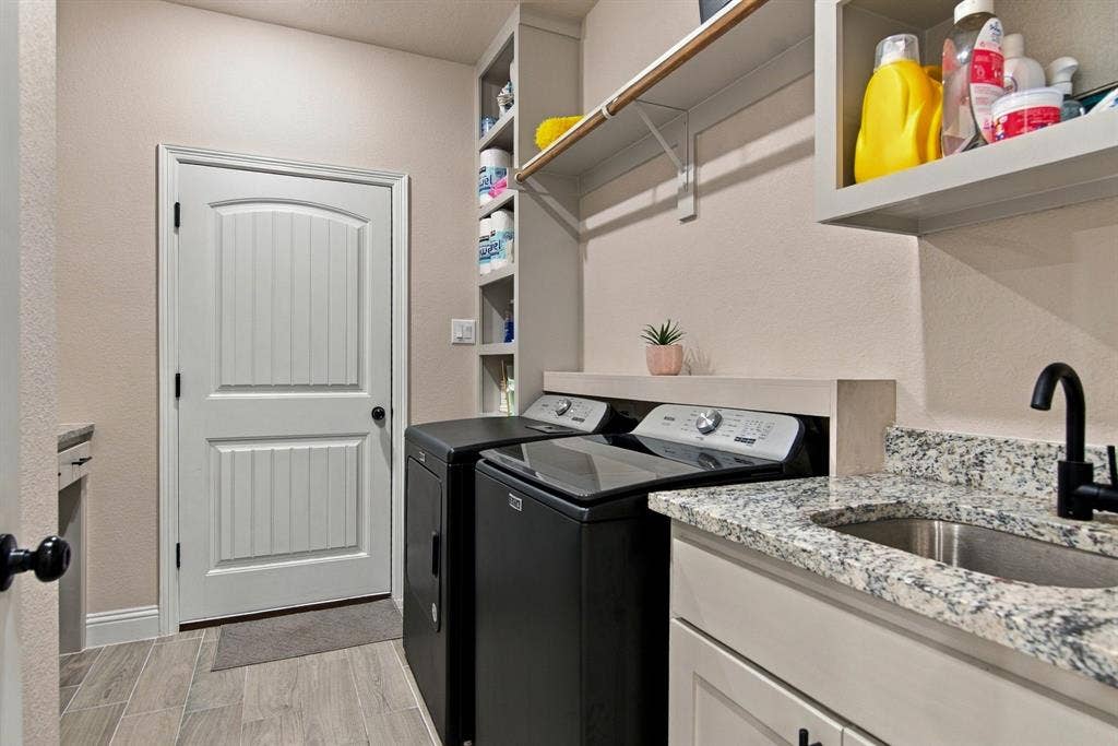 4822 Wichita Street, Granbury, TX 76048 Utility room featuring a built-in sink with a matte black faucet, granite-style countertop, and ample storage with shelving and cabinets