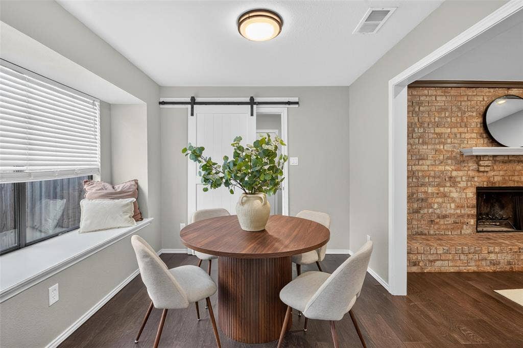 Recessed window seat, wood-finish flooring, white barn door, brick fireplace, and built-in lighting