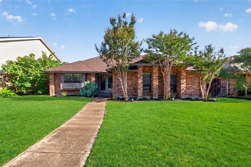 Brick exterior with a brown roof and mature landscaping
