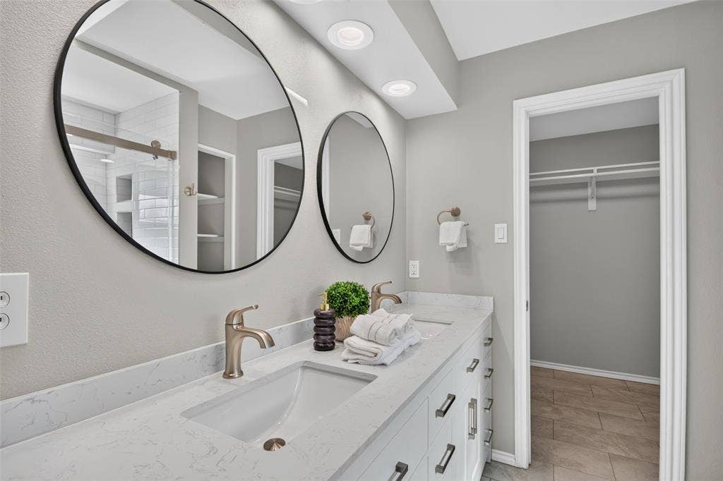 Dual vanity with integrated sinks, brushed bronze fixtures, and round black-framed mirrors