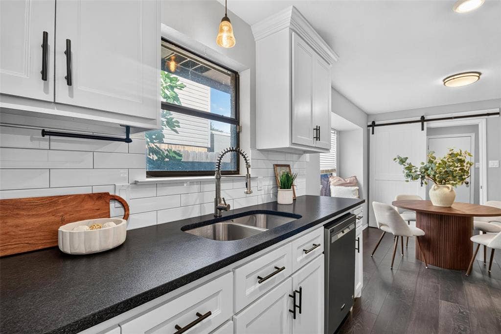 White shaker cabinetry, dark countertops, a subway tile backsplash, a stainless steel sink with a gooseneck faucet, and dark wood-finish flooring