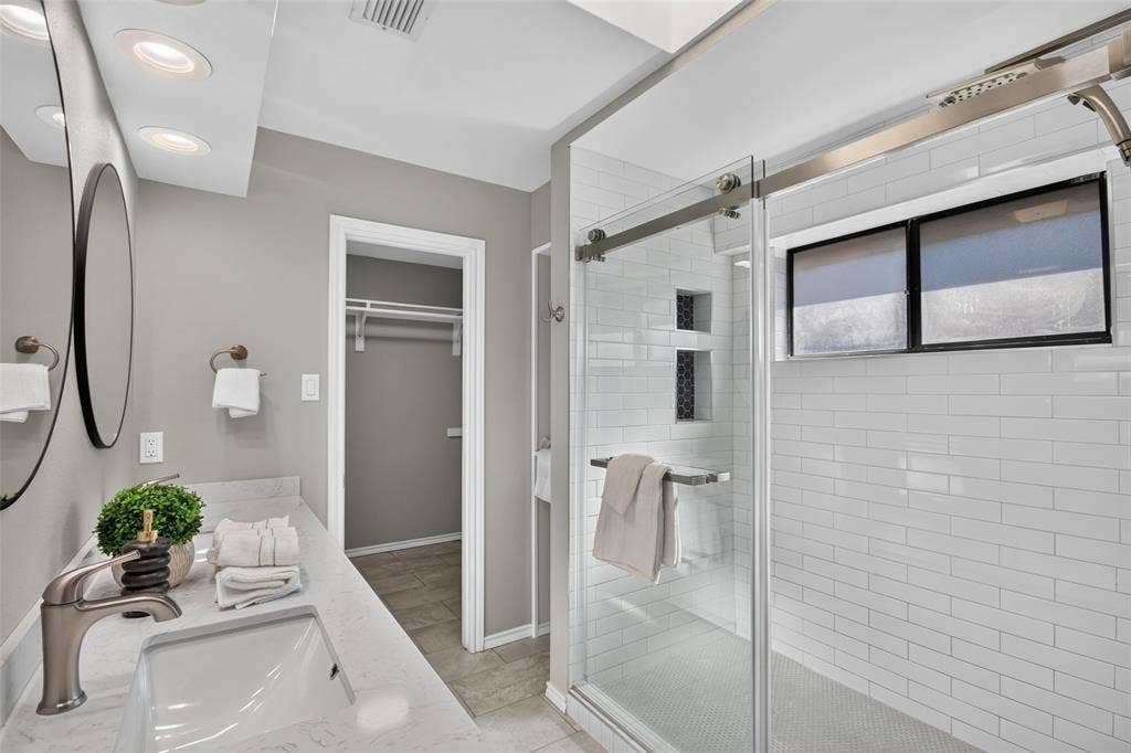 Bathroom featuring a vanity with an undermount sink and a polished chrome faucet, dual circular mirrors, and recessed lighting