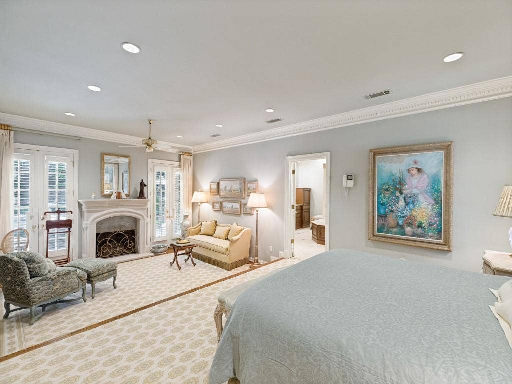 Recessed lighting, crown molding, double French doors, ornate fireplace with decorative screen, and a ceiling fan