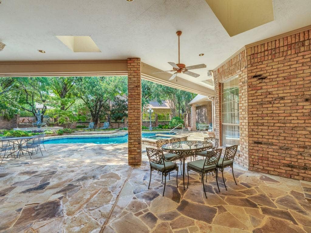 Covered patio featuring flagstone flooring, brick architectural elements, and recessed lighting