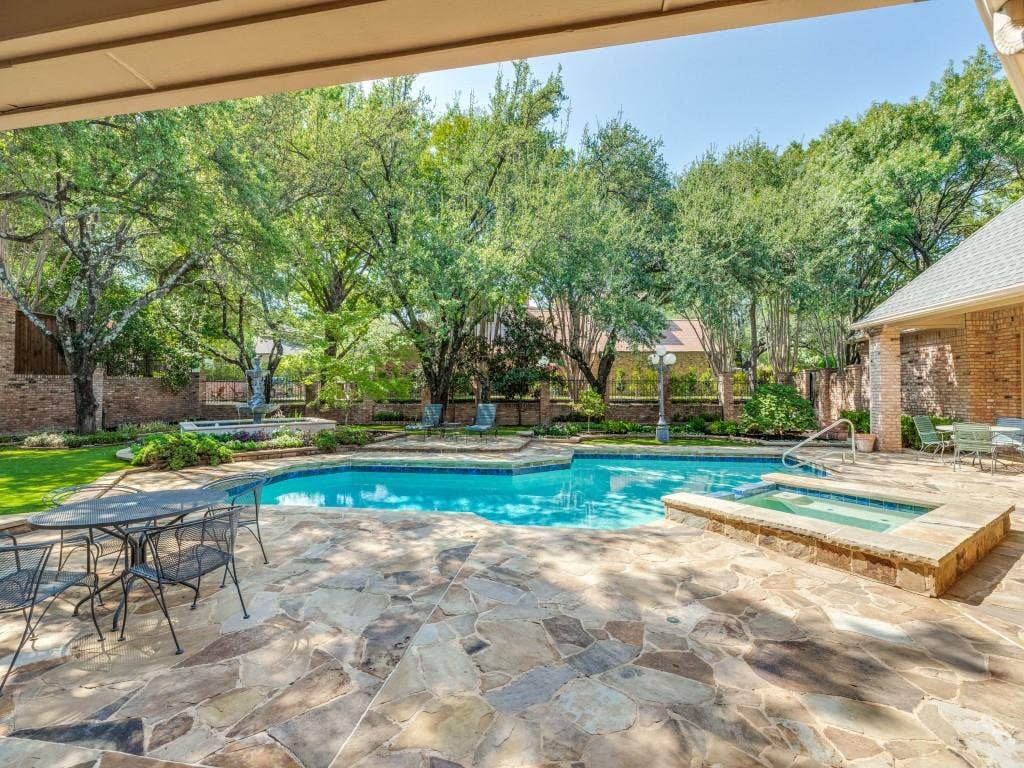 Freeform swimming pool with an integrated spa, surrounded by natural stone patio