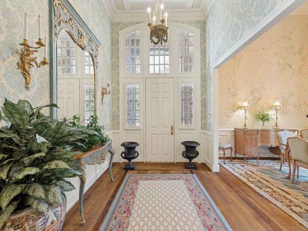 Grand entry with high ceilings, hardwood flooring, decorative wallpaper, and an ornate chandelier
