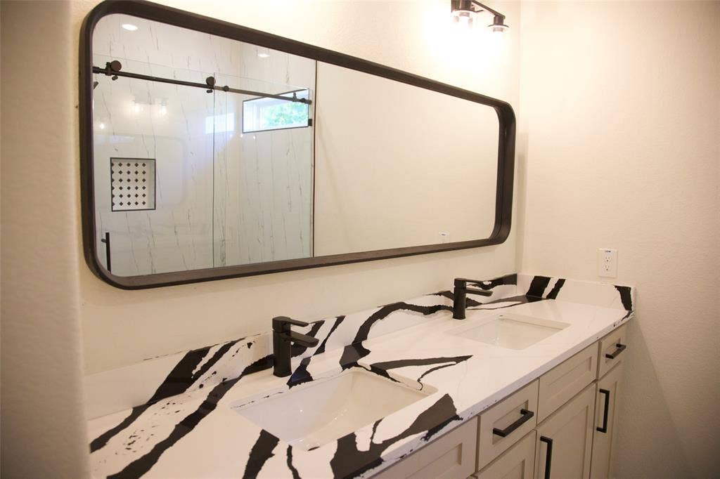 9432 PRAIRIEVIEW Drive, Crowley, TX 76134 Double vanity with black and white patterned countertop, matte black faucets, and undermount sinks