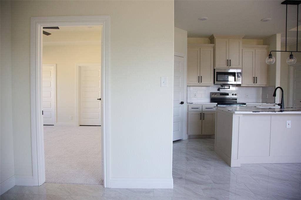 9432 PRAIRIEVIEW Drive, Crowley, TX 76134 Kitchen with light cabinetry, stainless steel appliances, a subway tile backsplash, and a central island with a sink and pendant lighting