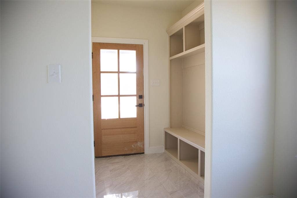 9432 PRAIRIEVIEW Drive, Crowley, TX 76134 Wood-paneled entry door with glass inserts, built-in storage bench with cubbies, and marble-finish tile flooring