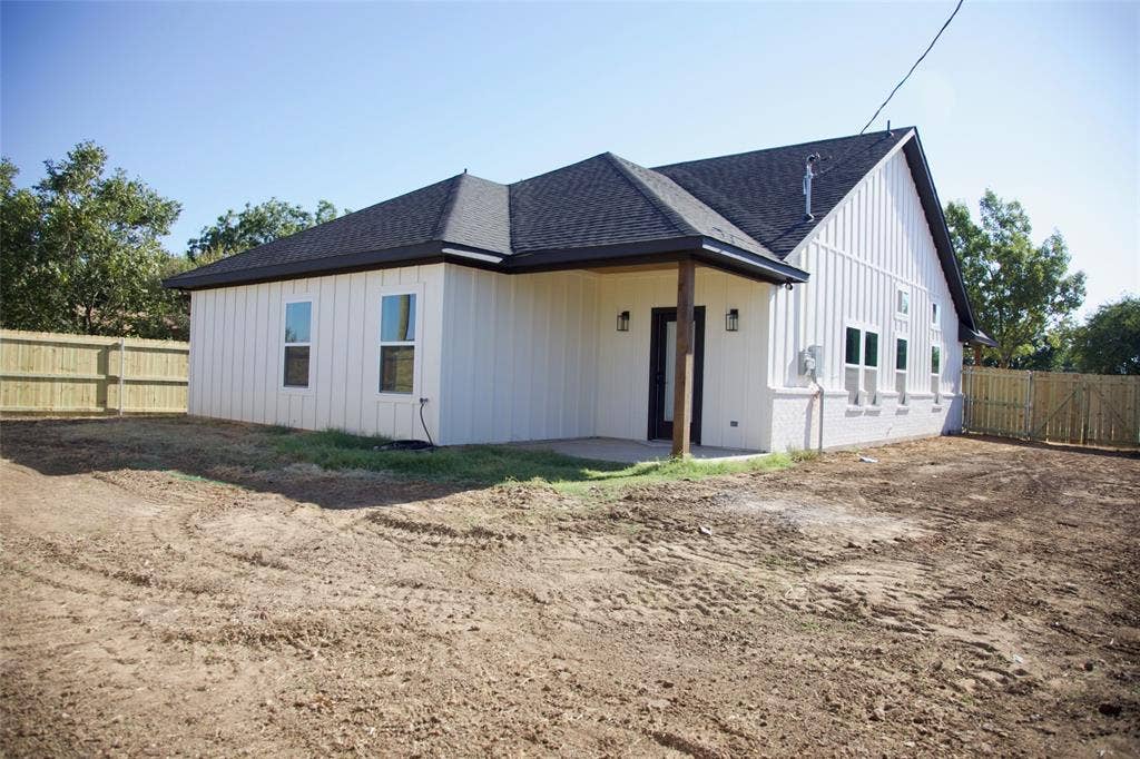 9432 PRAIRIEVIEW Drive, Crowley, TX 76134 Exterior featuring white board and batten siding, dark shingle roof, dark trim, and a covered porch