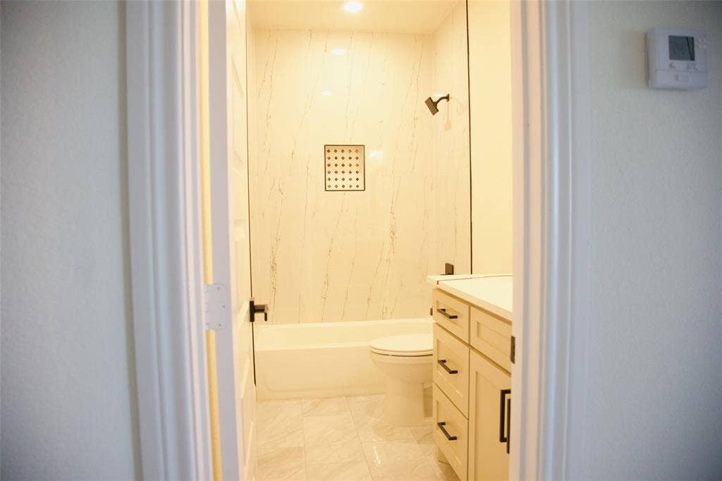 9432 PRAIRIEVIEW Drive, Crowley, TX 76134 Bathroom featuring a full tub with shower, integrated shower niche, glass shower partition, single vanity, and tiled flooring