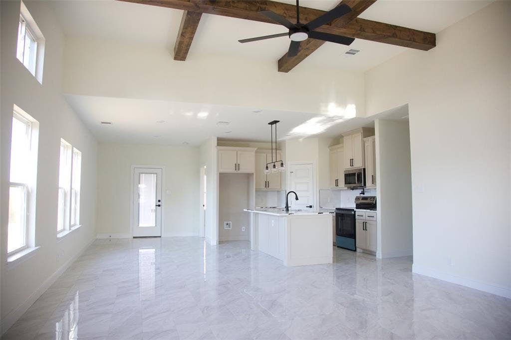 9432 PRAIRIEVIEW Drive, Crowley, TX 76134 Open-concept living space featuring high ceilings with exposed beams, an integrated kitchen with a central island, and modern pendant lighting