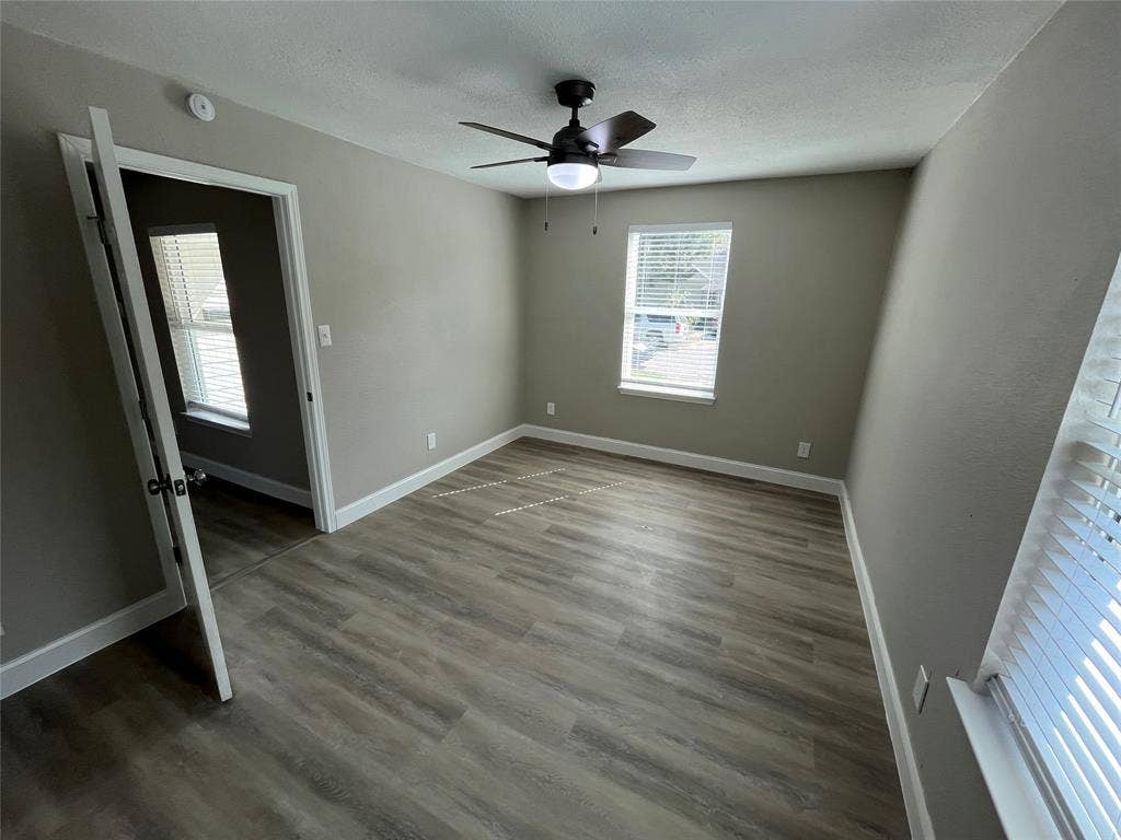 622 Austin Street, Grand Prairie, TX 75051 Neutral-toned interior featuring wood-finish flooring, dual windows with fitted blinds, and a central ceiling fan with integrated lighting