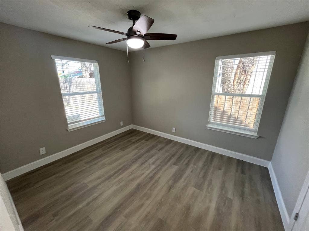 622 Austin Street, Grand Prairie, TX 75051 Neutral-toned walls paired with wood-finish flooring, dual windows, and a ceiling-mounted light fixture with a fan