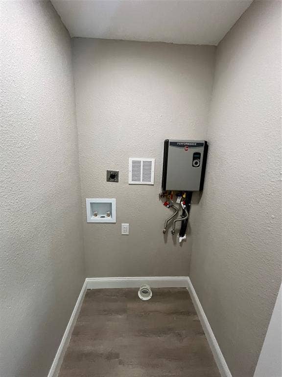622 Austin Street, Grand Prairie, TX 75051 Dedicated utility area featuring wood-finish flooring, a wall-mounted tankless water heating unit, and integrated plumbing hookups