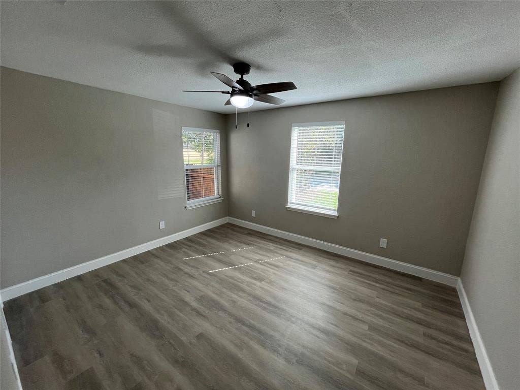 622 Austin Street, Grand Prairie, TX 75051 Room featuring wood-finish flooring, dual windows with blinds, and a central ceiling fan with integrated lighting