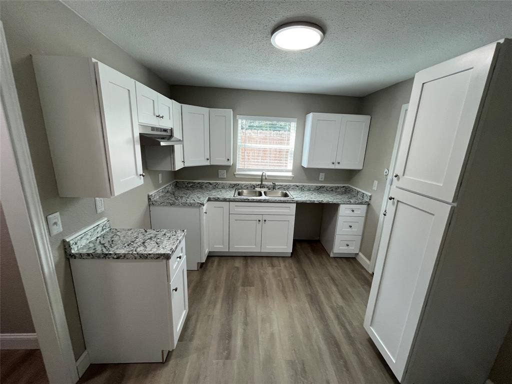 622 Austin Street, Grand Prairie, TX 75051 Kitchen featuring white shaker-style cabinetry, patterned stone-finish countertops, stainless steel dual-basin sink, and wood-finish flooring