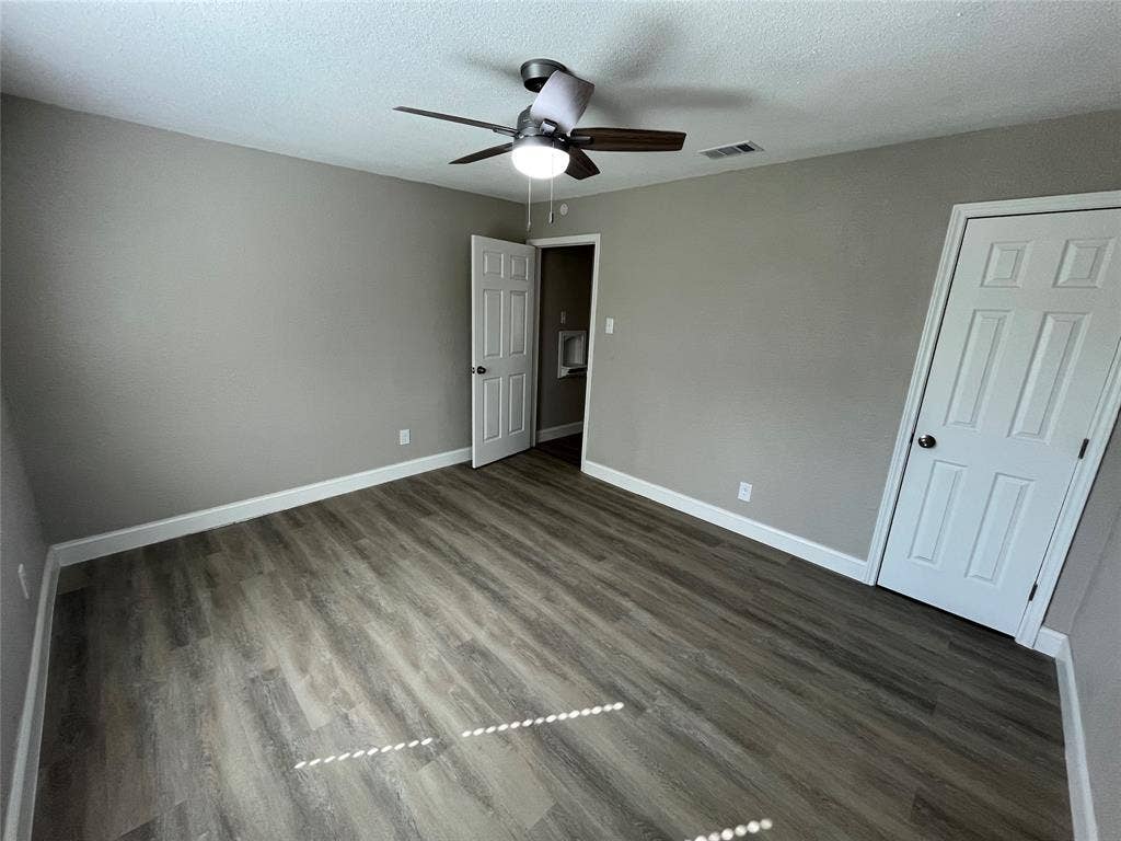 622 Austin Street, Grand Prairie, TX 75051 Room featuring wood-finish flooring, neutral wall paint, a ceiling fan with integrated lighting, and two six-panel interior doors