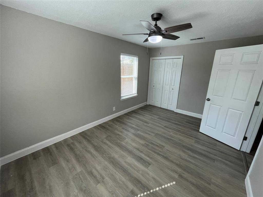 622 Austin Street, Grand Prairie, TX 75051 Room featuring wood-finish flooring, a ceiling fan with integrated lighting, a single window, and a white six-panel door