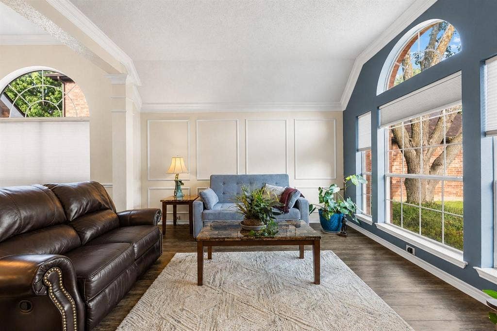521 Palm Desert Drive, Garland, TX 75044 Vaulted ceiling, paneled accent wall, wood-finish flooring, arched window, and large bay windows