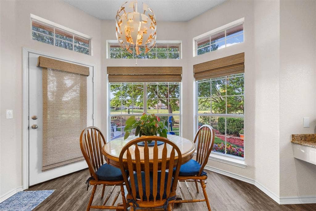 521 Palm Desert Drive, Garland, TX 75044 Bay window with upper transom windows, wood-finish flooring, and a contemporary chandelier