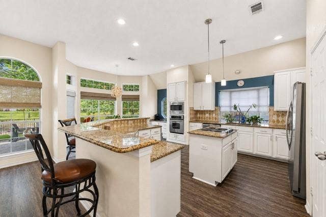 521 Palm Desert Drive, Garland, TX 75044 Kitchen featuring wood-finish flooring, white cabinetry, a central island with cooktop, and built-in stainless steel appliances