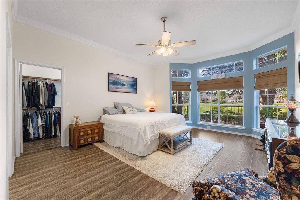521 Palm Desert Drive, Garland, TX 75044 Bay window with multiple windows, crown molding, wood-finish flooring, ceiling fan, and walk-in closet