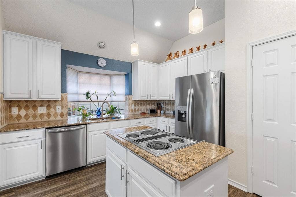 521 Palm Desert Drive, Garland, TX 75044 Kitchen with white shaker-style cabinetry, stainless steel appliances, granite countertops, patterned tile backsplash, and wood-finish flooring