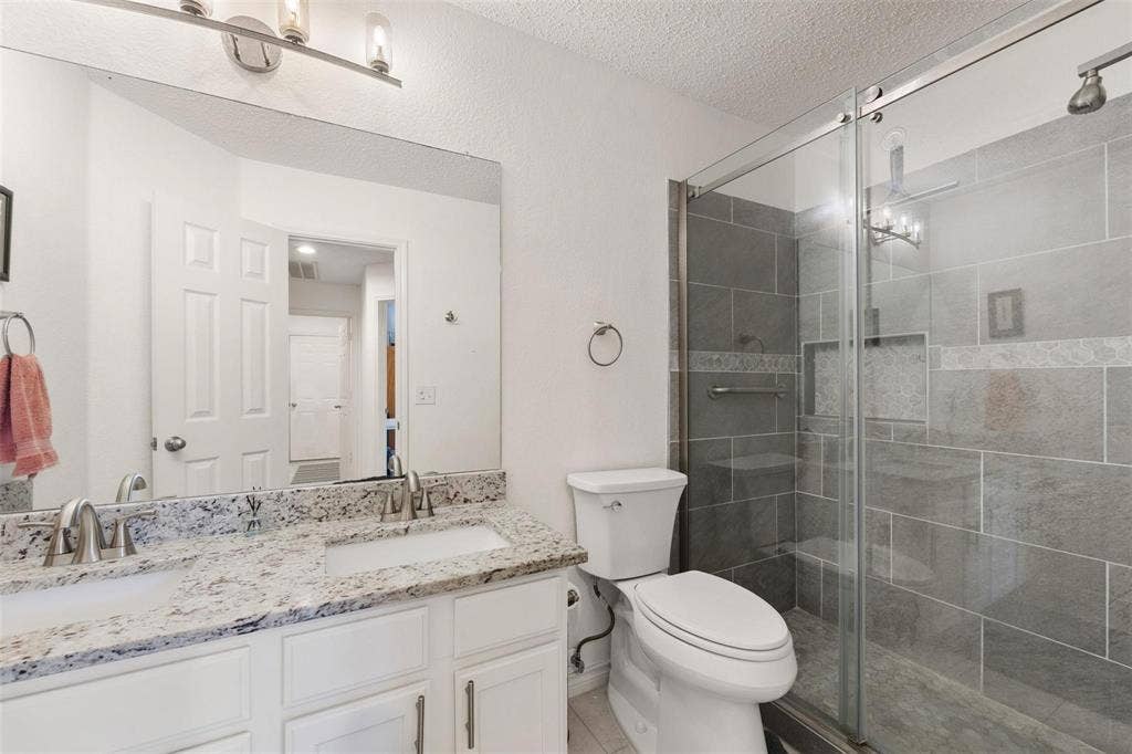 521 Palm Desert Drive, Garland, TX 75044 Dual vanity with stone-finish countertop, white cabinetry, and undermount sinks