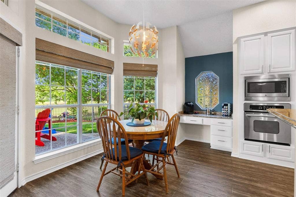 521 Palm Desert Drive, Garland, TX 75044 Wood-finish flooring, built-in stainless steel microwave and oven, white cabinetry, granite countertop, and large windows with transom architectural details