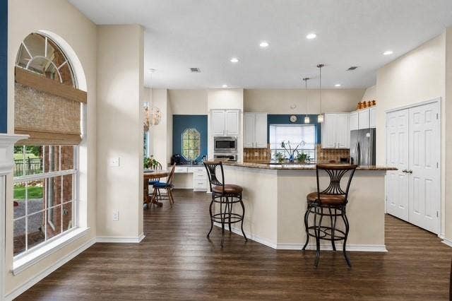 521 Palm Desert Drive, Garland, TX 75044 Spacious kitchen featuring an expansive counter-height island, wood-finish flooring, white cabinetry, and recessed lighting