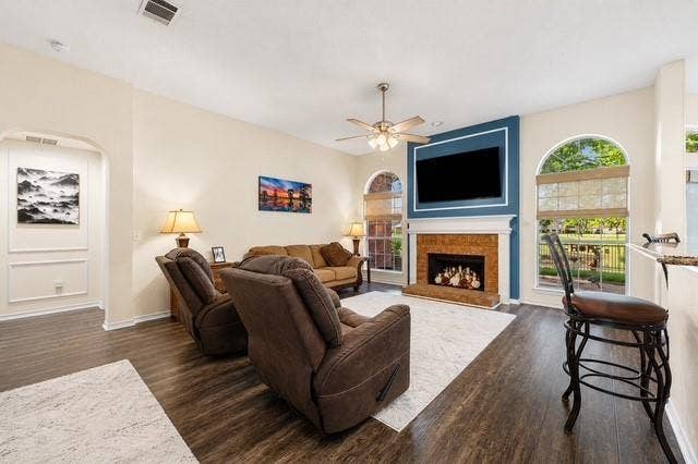 521 Palm Desert Drive, Garland, TX 75044 Living area featuring wood-finish flooring, an arched entryway, a ceiling fan with light fixture, and arched windows with blinds
