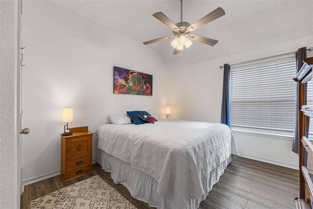 521 Palm Desert Drive, Garland, TX 75044 Vaulted ceiling, wood-finish flooring, ceiling fan with integrated lighting, window with blinds, and white walls