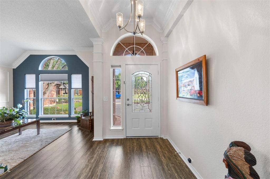 521 Palm Desert Drive, Garland, TX 75044 Wood-finish flooring, decorative front door with arched transom, chandelier lighting, and a large picture window with an arched transom