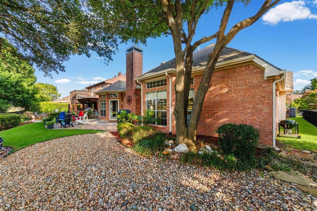 521 Palm Desert Drive, Garland, TX 75044 Brick exterior with a stone patio, mature landscaping, and a gravel pathway