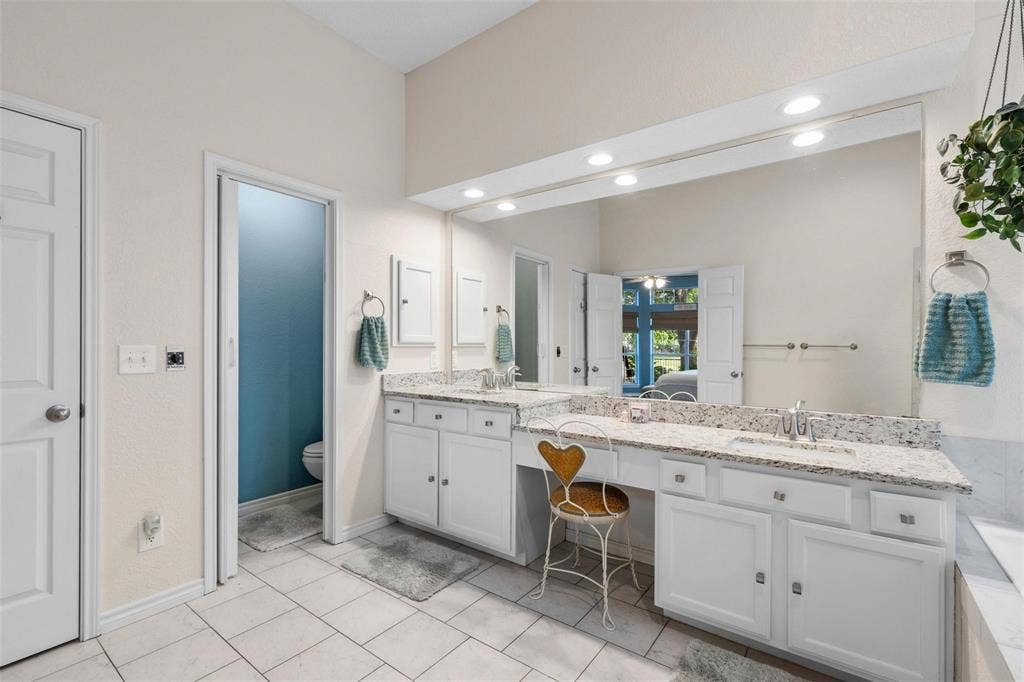 521 Palm Desert Drive, Garland, TX 75044 Dual vanity with light-colored countertops, white cabinetry, and undermount sinks