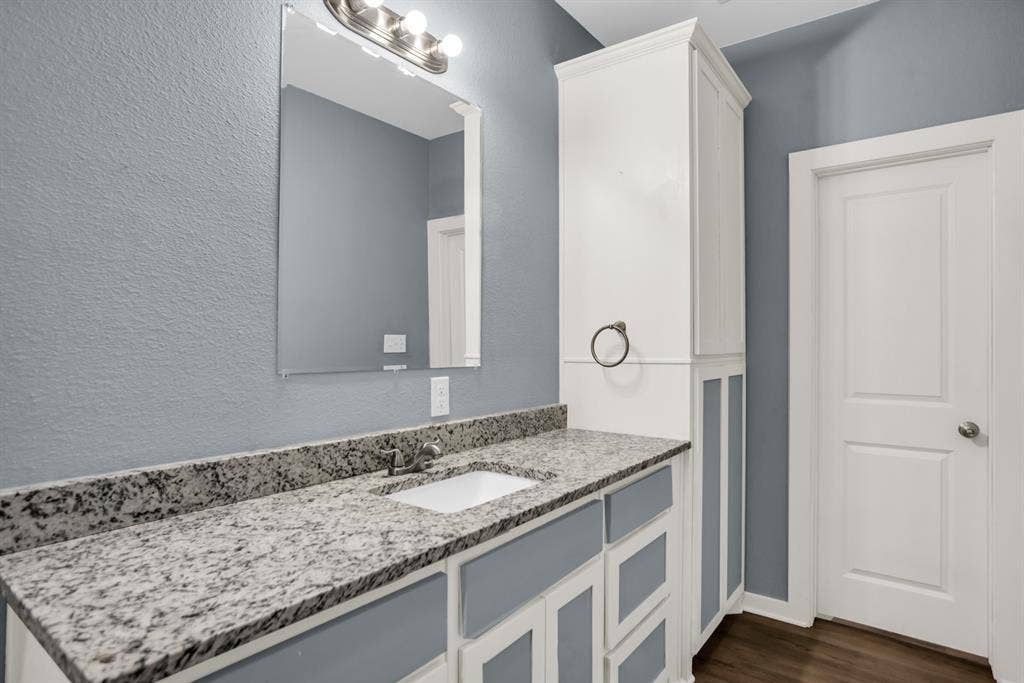 440 Pecan Hollow, Garrett, TX 75119 Bathroom vanity featuring a speckled countertop, undermount sink, and brushed nickel faucet