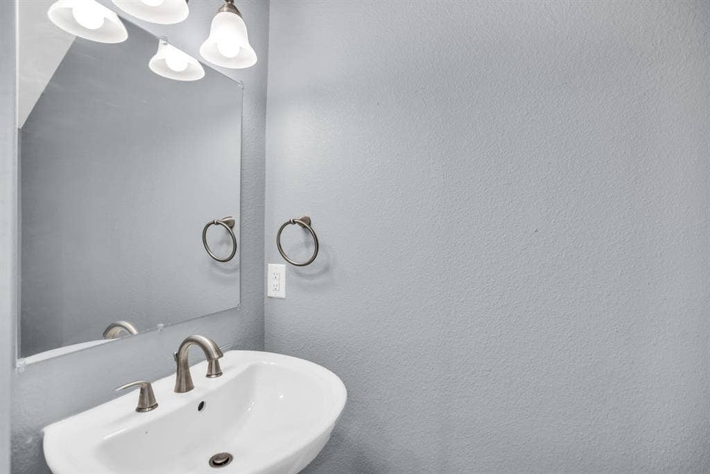 440 Pecan Hollow, Garrett, TX 75119 White pedestal sink with a brushed nickel faucet, framed by a rectangular mirror