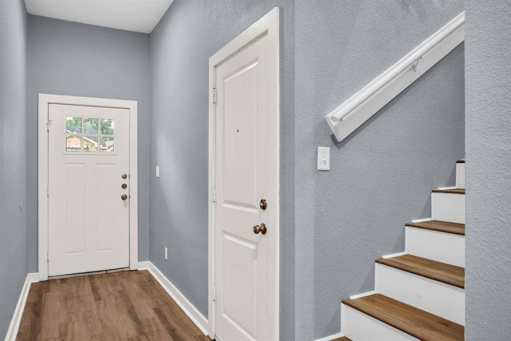 440 Pecan Hollow, Garrett, TX 75119 Entryway featuring wood-finish flooring, a white front door with multiple glass panes, and a white staircase with wood-finish treads and a white handrail