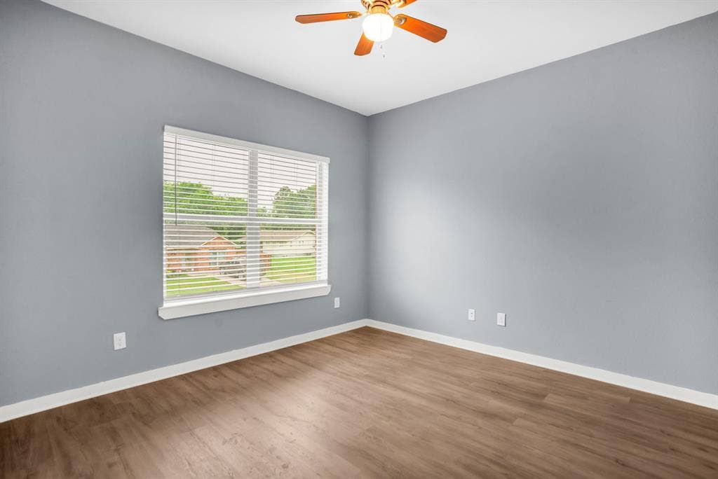 440 Pecan Hollow, Garrett, TX 75119 Spacious room featuring wood-finish flooring, a ceiling fan with integrated lighting, and a large window with blinds
