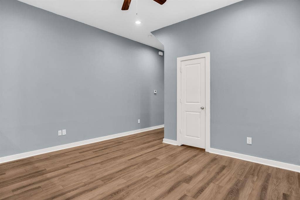 440 Pecan Hollow, Garrett, TX 75119 Spacious room featuring light blue walls, wood-finish flooring, and white trim