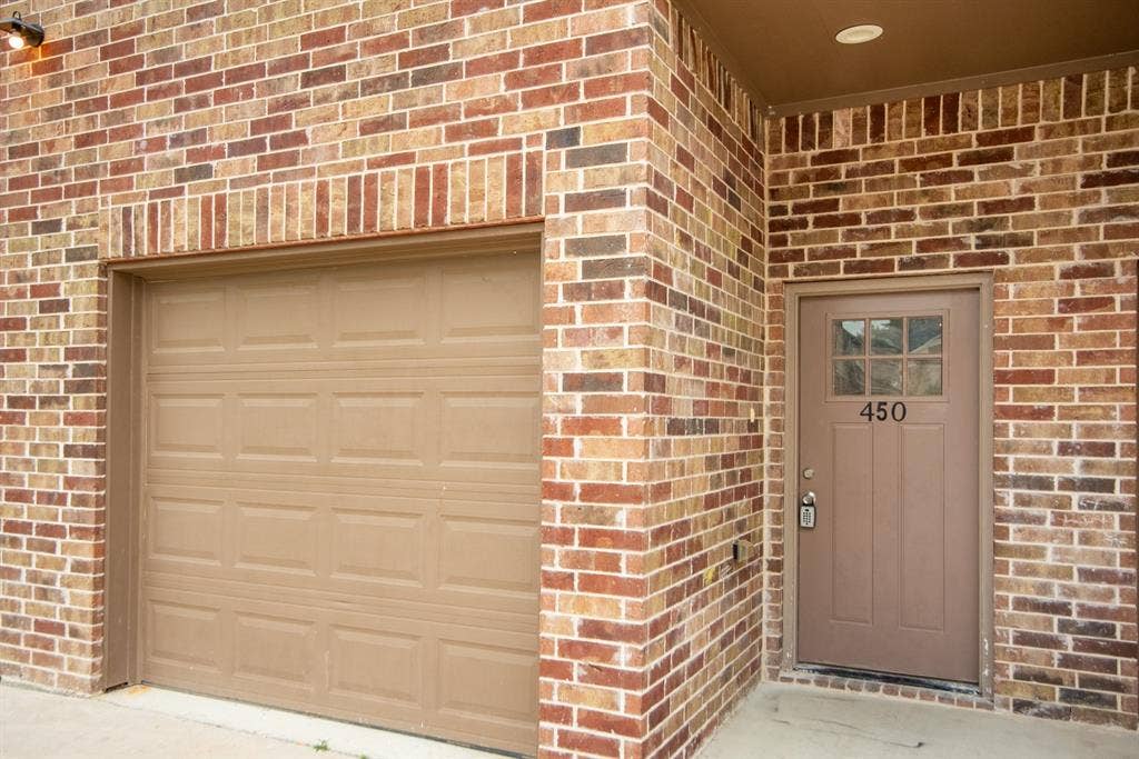 440 Pecan Hollow, Garrett, TX 75119 Multicolor brick exterior featuring a tan panel garage door and a complementary tan front entry door
