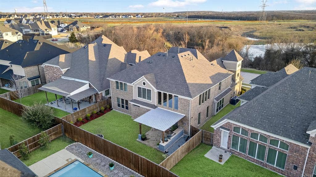 Expansive backyard with a covered patio, manicured lawn, and privacy fencing