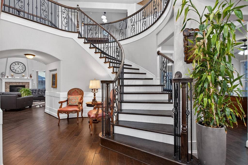 Curved staircase with wrought iron balusters and dark wood-finish treads