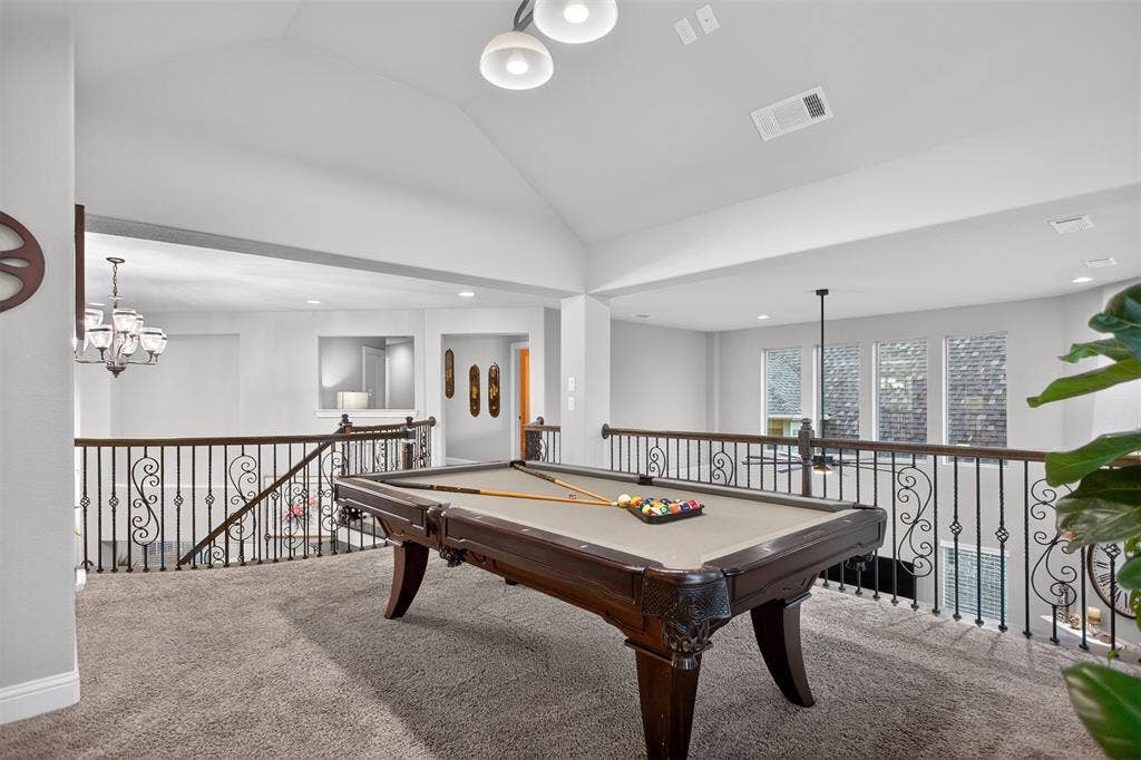 Spacious loft area with vaulted ceilings, recessed lighting, and ornate wrought iron railings